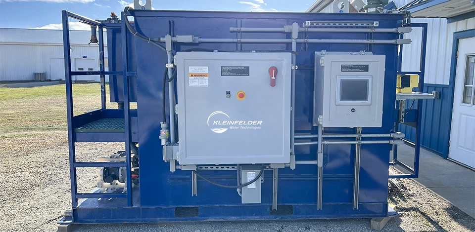 Water treatment equipment in blue container with gray control panel sitting in grass lot