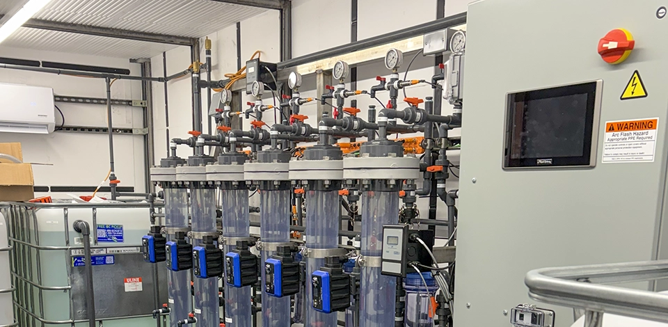 Interior view of water testing equipment in modular container with tubes, piping, and control panel